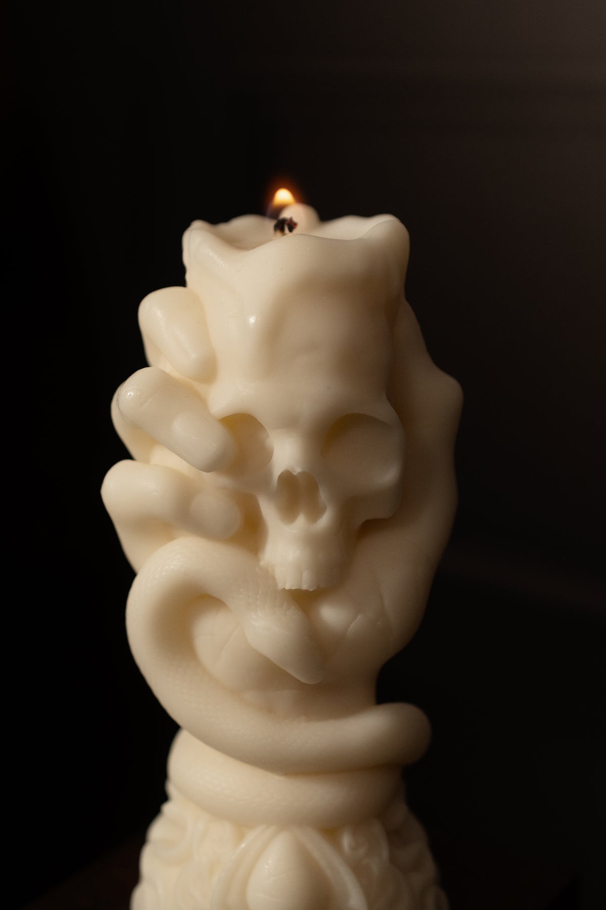 Skeletal hand wrapped in a serpent, sculpted as a lit candle